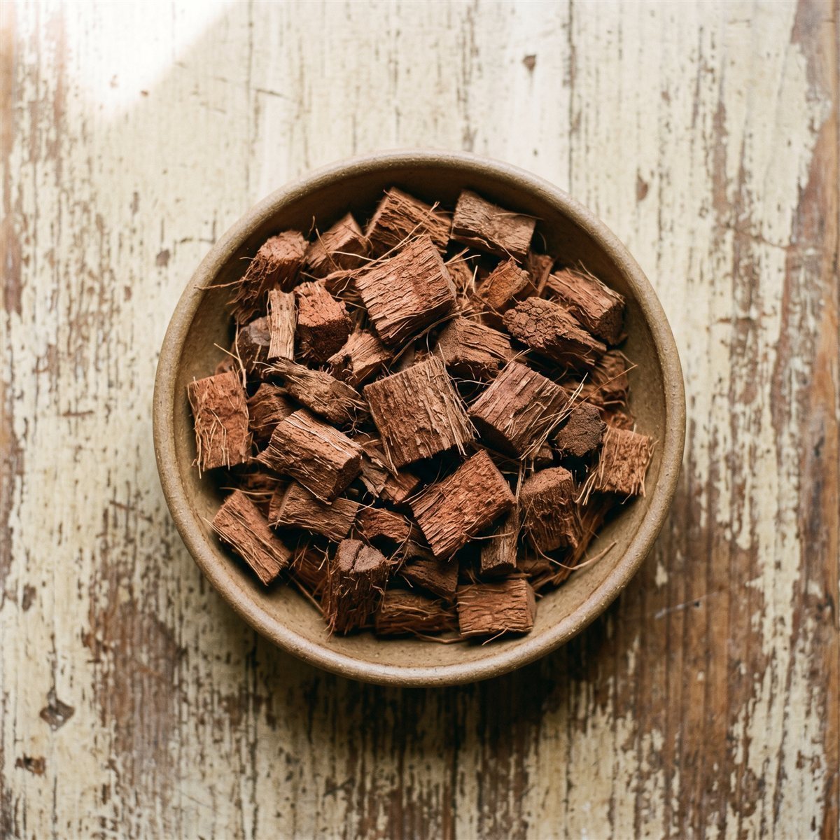 Chunky coconut husk coco chips in a bowl on a weathered wood surface