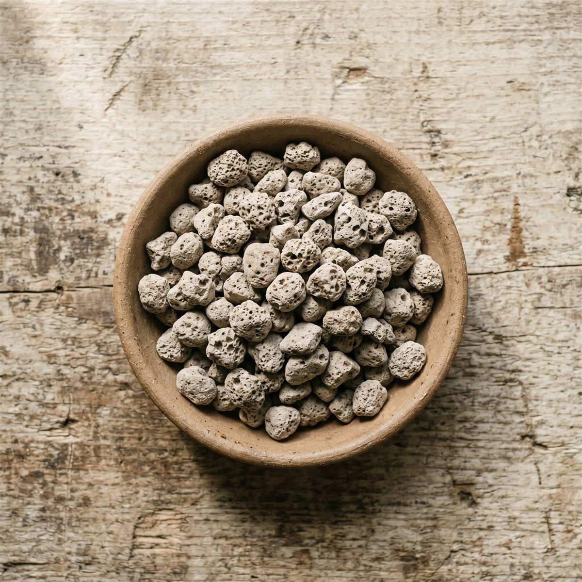 Pumice in a ceramic bowl on a weathered wood surface